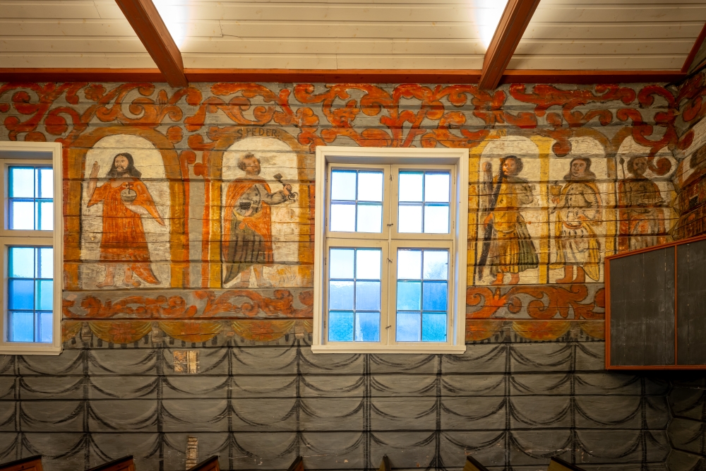Figurar måla på veggen i tømmerkyrkja.